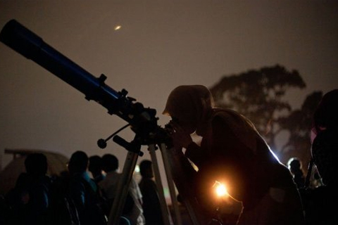 Người quan sát nguyệt thực qua kính thiên văn tại Jakarta. Ảnh: AFP