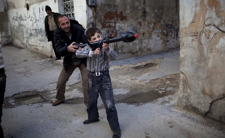 Một người đàn ông dạy cậu bé cách sử dụng súng phóng lựu đạn tại thành phố Idlib, miền Bắc Syria.