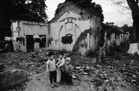 Những em bé chạy chơi bên một khu nhà bị bom Mỹ tàn phá trong chiến tranh.