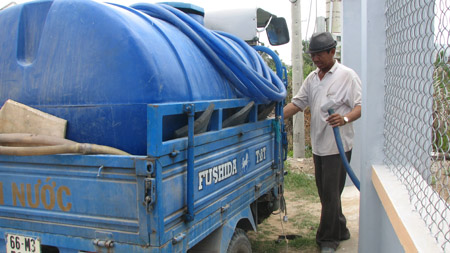  Ông Tám Chưa đang gắn ống xả nước sạch từ xe xuống cho một hộ dân ở ấp 3, xã Phước Vĩnh Tây.