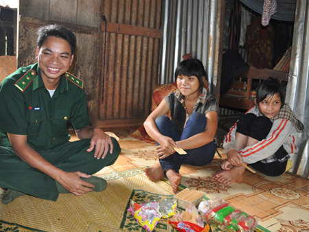  Trung tá Rah Lan Toanh (trái) đang trò chuyện với cháu Siu H’Ly (giữa). Siu H’ly cho biết luôn nhận được sự chăm sóc của các “cha bộ đội”. 