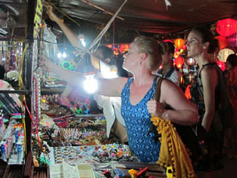 Du khách lựa chọn những đồ vật được bày bán tại chợ đêm ở Hội An. (ảnh: Trà Xanh)