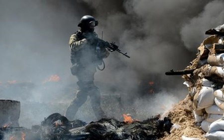 Một binh sĩ Ukraine đứng giữa biển khói lửa sau cuộc đụng độ với lực lượng Dân quân ở Đông Ukraine tại một trạm kiểm soát.
