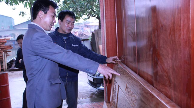 Ông Quang (trái) giới thiệu sản phẩm ở xưởng mộc  của mình.