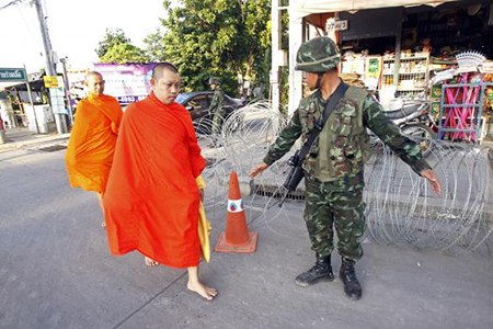 Những nhà sư đi bộ qua  một trạm kiểm soát quân sự gần địa điểm cắm trại của phe 