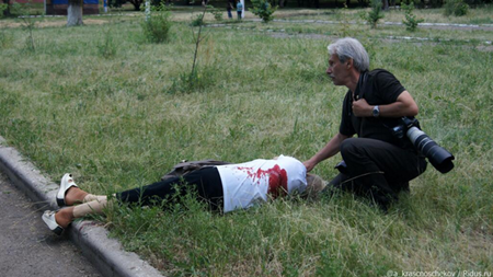 Một nạn nhân nằm chết trên bãi cỏ với vết thương ở lưng đẫm máu.