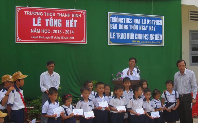 Thầy Cao Văn Đưa (phải) trao quà cho các em học sinh nghèo xã Thanh Bình. 