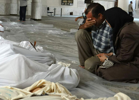 Một người đàn ông và người phụ nữ Syria than khóc bên những xác chết của những đứa trẻ được cho là nạn nhân của cuộc tấn công khí độc cuối tháng 8 tại Damascus, Syria. 