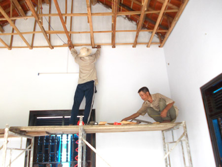 Ông Hồ Thành Diệp (ngồi) đang cùng thợ thi công trần nhà.