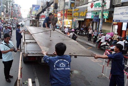 Các công nhân Công ty Thoát nước Đô thị thành phố dùng tấm sắt che hố sụp lại để không ảnh hưởng đến phương tiện lưu thông.