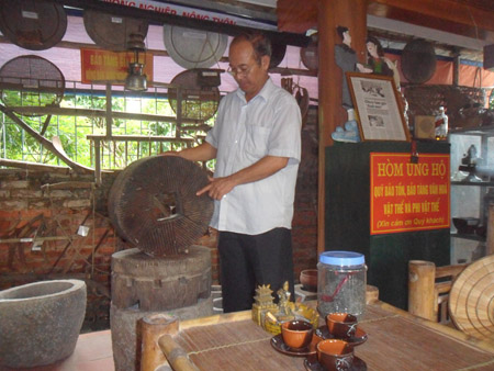 Ông Nguyễn Công Đồn bên cạnh chiếc cối xay bằng gỗ.