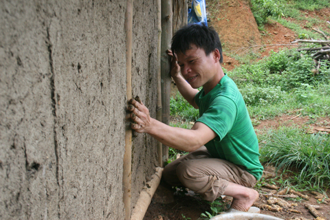 Anh Lệ dùng phân trâu trát vào những chỗ còn hở của bờ vách. 