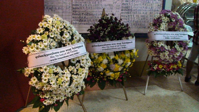 Vòng hoa chia buồn với dòng chữ “May the soul of all victims” của chính quyền tỉnh Champasak gửi đến nhà tang lễ chùa Trung Hoa Pakse chia buồn với gia đình nạn nhân.