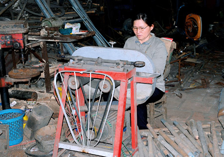 Bà Trần Thị Hòe với chiếc máy rèn do bà tự chế.