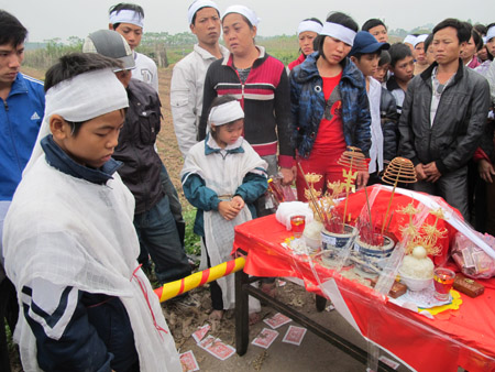 Hai đứa con thơ của vợ chồng Chí, Hạnh trước hài cốt bố mẹ.