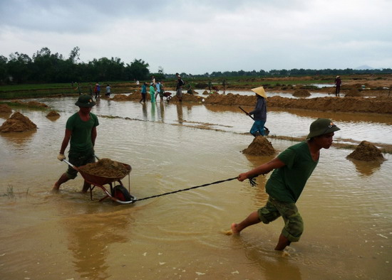 Cán bộ, chiến sĩ Lữ đoàn pháo binh 572 (Quân khu 5) giúp người dân xã Nhơn Phúc (thị xã An Nhơn) khắc phục sa bồi thủy phá, kịp gieo sạ vụ ĐX 2013-2014. (Nguồn ảnh: Báo Bình Định)