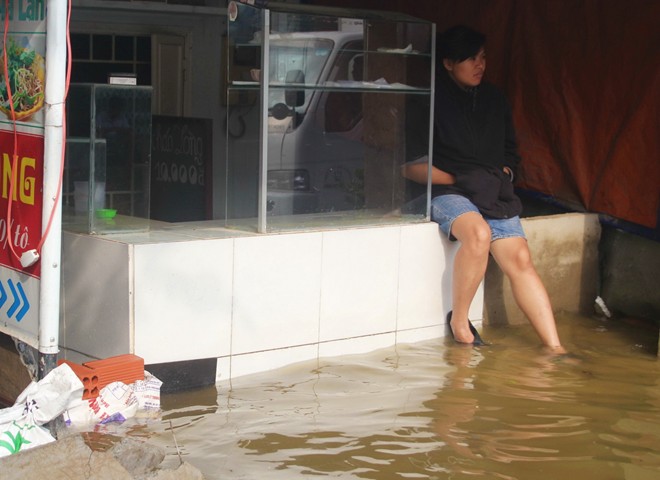 Hàng quán đóng cửa, chủ quán ngồi buồn nhìn dòng nước đen.