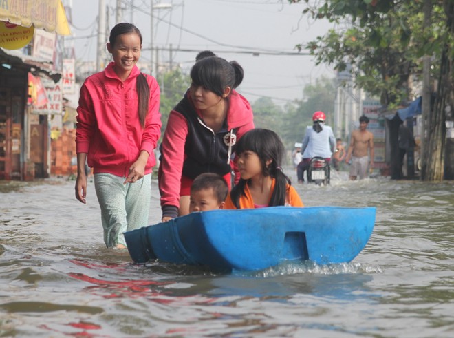 Trẻ em dùng thùng phuy bơi trên đường.