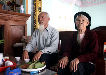 Bà cụ Đỗ Thị Loan, 92 tuổi, cùng con trai là ông Nguyễn Văn Vượng kể về những câu chuyện của làng. Ảnh: Phan Dương.