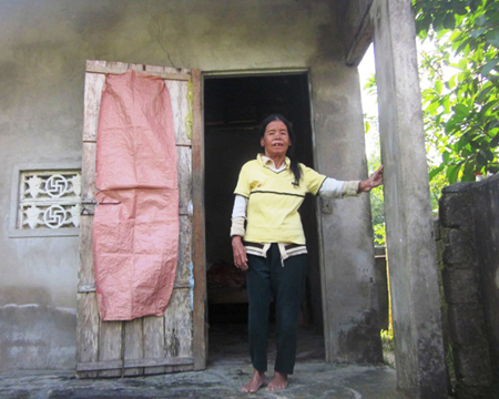 Chị Nguyễn Thị Tẻo bên căn nhà nhỏ lụp xụp và tồi tàn