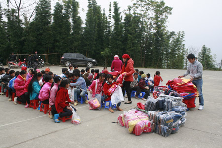Các thầy cô giáo phân phát quần áo, chăn mền cho các em học sinh.