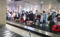 Hành khách vạ vật ở sân bay Tân Sơn Nhất rạng sáng 7-2 chờ lấy hành lý, gọi xe