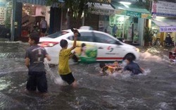 Trẻ em nô đùa, bơi trong nước ngập trên đường ở TP.HCM